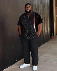 a man standing in front of a black wall with his hands on his hips wearing white shoes