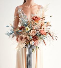 a woman holding a large bouquet of flowers in her hands and wearing a long dress