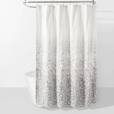 a white shower curtain with black and white dots on the bottom, hanging from a metal rod