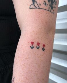 a woman's arm with tattoos on it, including flowers and a ladybug