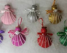 christmas ornaments are lined up in rows on a white tablecloth with beads and bows