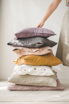 a stack of pillows sitting on top of each other next to a woman's hand