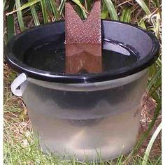 a black bucket with a brown arrow sticking out of it's side in the grass