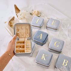 a person is holding an open suitcase with jewelry in it on a white tablecloth