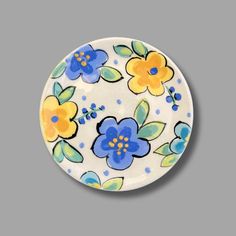 a blue and yellow flowered plate on a gray background with white trimmings