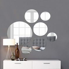 a white dresser sitting next to a mirror with four circular mirrors on top of it