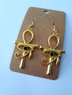 Dangle earrings made with gold plated pewter in ankh and eye of Horus design, with black rhinestone eye.  Earrings are 2 1/2 inches long, lead and nickel free, and can be made into clips. Nickel-free Ankh Gold Earrings, Gold Ankh Metal Jewelry, Gold Ankh Shaped Metal Jewelry, Elegant Ankh-shaped Metal Jewelry, Ankh-shaped Metal Earrings For Gift, Ankh Shaped Metal Earrings For Gift, Nickel-free Ankh Elegant Jewelry, Nickel-free Ankh Shaped Elegant Jewelry, Nickel-free Ankh Jewelry