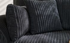 a black couch with two pillows on it's back and one pillow that has been turned down