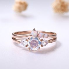 an opal and diamond ring on a white surface with other opals in the background