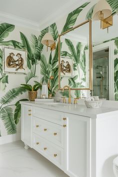 the bathroom is decorated with tropical wallpaper and gold fixtures, along with a large mirror