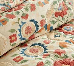 an image of a bed with flowers on the comforter and pillow cases in different colors