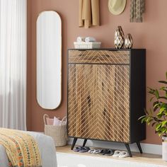 a room with a wooden cabinet, mirror and plants on the side table in front of it