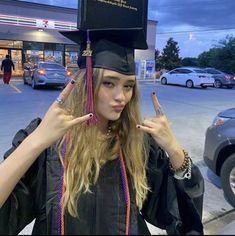 a woman in graduation cap and gown holding up two fingers