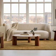 a living room scene with focus on the couch and coffee table in front of large windows