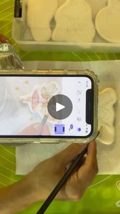 a person holding a cell phone in front of some doughnuts on a table