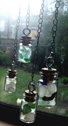 three jars filled with sea glass sitting on a window sill