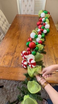 a woman is decorating a christmas garland on a table