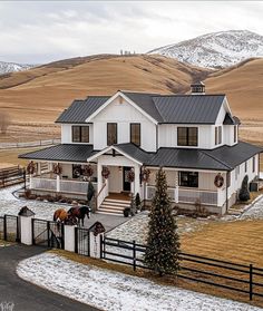 a large white house with a horse in the front yard and snow on the ground