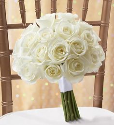 a bouquet of white roses is sitting on a chair