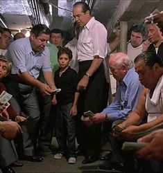 a group of people sitting around each other in a room with one man holding a cell phone