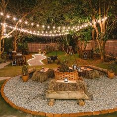 an outdoor patio with lights strung over it and hay bales on the ground, surrounded by greenery