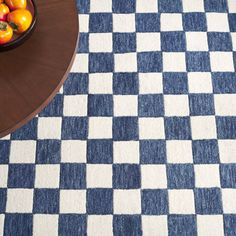 a bowl of fruit sitting on top of a blue and white checkered table cloth