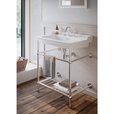 a white sink sitting next to a window on top of a wooden floor in a bathroom