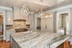 a large kitchen with marble counter tops and white cabinets