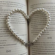 an open book with a heart made out of pearls and a cross on it's cover