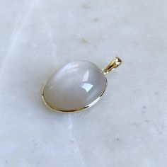 This stunning Pendant is set in 14k Solid Yellow Gold with Natural White Moonstone with utmost precision. It is a unique gemstone Pendant for nearly every occasion and is completely hassle-free jewelry. ITEM DETAILS: * GEM: White Moonstone  * GEM Size: 15x20mm * GEM Shape: Oval  * Gem Weight: 20.18 carats * Gold Purity: 14KT * Gold Weight: 0.62 gram * Total Weight of the Pendant: 4.66 gram The Gold purity is guaranteed and it comes with authentic 14KT gold hallmark. Since my items are handmade, they are absolutely nickel and lead free. CUSTOMIZATION: * Gemstone customization is available and it can be substituted with a gem of your choice. Kindly message me for the same. PACKAGING * The Pendant comes with layers of safe and secure wrapping along with Free handmade jewelry box with every pu Maximalist Jewelry, Handmade Jewelry Box, White Moonstone, Bezel Pendant, Birthstone Pendant, June Birthstone, Moonstone Jewelry, Moonstone Pendant, Unique Gemstones