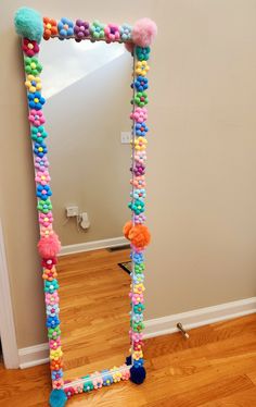 a mirror with pom - poms on it in the middle of a room