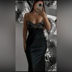 a woman taking a selfie in front of a mirror wearing a black dress with sequins on it