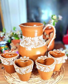 a group of clay pots and cups on a wicker tray