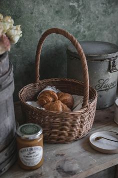 some bread and jams in a basket on a table