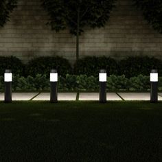 four lights are lit up in the grass at night