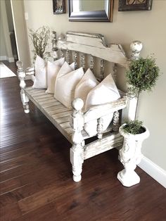 a white bench with pillows and plants on it