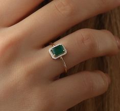 a woman's hand with a ring on it and a green stone in the middle