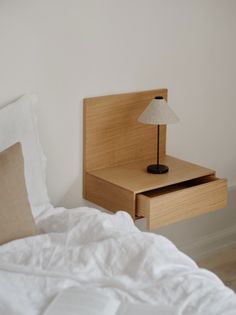 a bed with white sheets and a wooden night stand