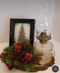 an old fashioned lamp is decorated with pine cones and red berries for the holiday season