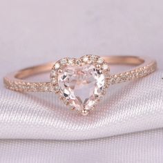 a heart shaped diamond ring on top of a white cloth