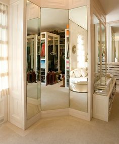 a large mirrored closet in the corner of a room with white walls and flooring