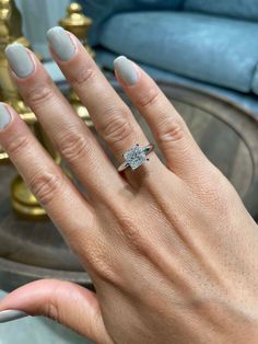 a woman's hand with a diamond ring on her finger and white nail polish