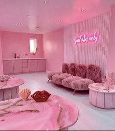 a pink room with two couches and a table in the middle that has a shell on it