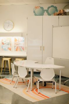 a white table and chairs in a room with colorful rugs on the floor next to cabinets