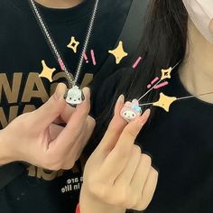 a woman is holding onto some fake stars and pins on her nails while wearing a black t - shirt