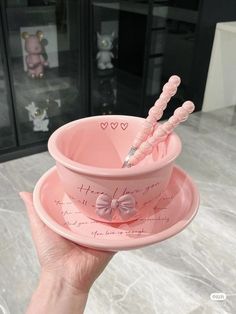 a person holding a pink bowl with two toothbrushes in it and writing on the side