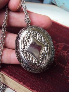 This is a vintage locket necklace from around the 1970s. It is an antique silver tone metal, with a Victorian style picture on the front, and the back has a raised ornate design. The locket is in wonderful condition, there is a glare from the camera in the pictures. I have added a matching long antique silver tone chain, which is 30 in. long. The locket is 2 in. long, and 1 3/4 in. wide. The necklace is in great condition. Thank you for looking! Vintage Antique Silver Oval Locket Necklace, Vintage Oval Locket Necklace In Antique Silver, Vintage Antique Silver Necklace With Round Pendant, Vintage Metal Locket Necklace With Antique Finish, Victorian Locket Necklace In Antique Silver, Antique Silver Medallion Locket Necklace With Vintage Charm, Victorian Antique Silver Locket Necklace, Vintage Silver Necklaces With Vintage Charm, Vintage Silver Necklace With Vintage Charm