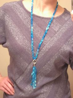 a woman is wearing a necklace with blue beads and a beaded tassel on it