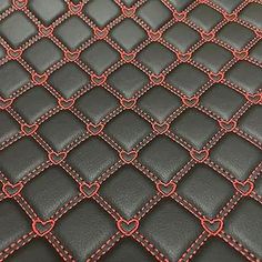 a close up view of a black leather surface with red stitching and hearts on it