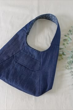 a blue bag sitting on top of a white table next to a green leafy plant